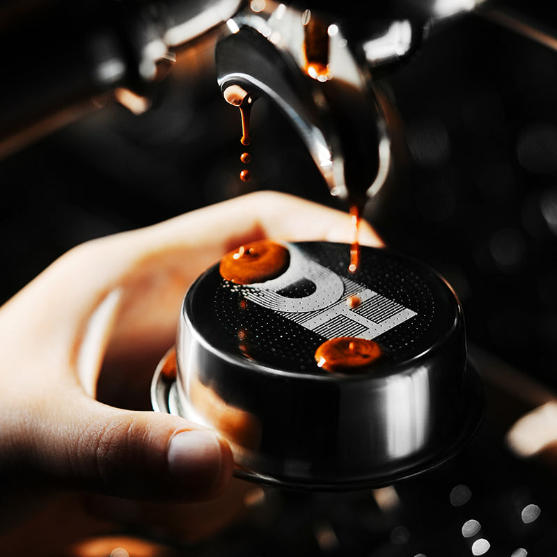 MHW-3BOMBER FB5648 silver DH basket held under an espresso spout; machine, portafilter and coffee are not included.