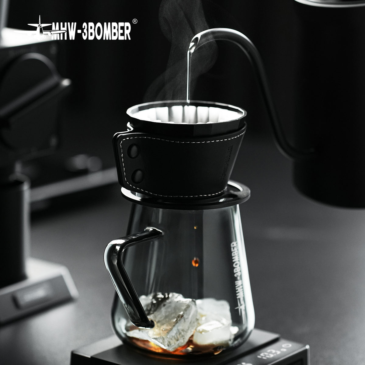 MHW-3BOMBER Meteorite Dripper FC6555B, Obsidian Black, pouring over a glass server with ice; server and kettle are props