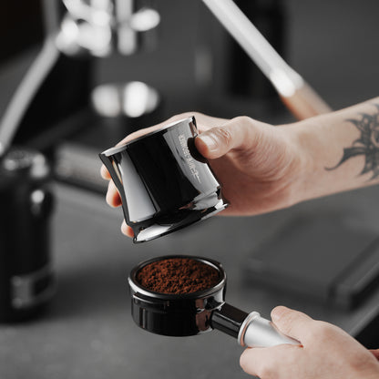 MHW-3BOMBER silver FlowLight dosing tool held above an espresso basket