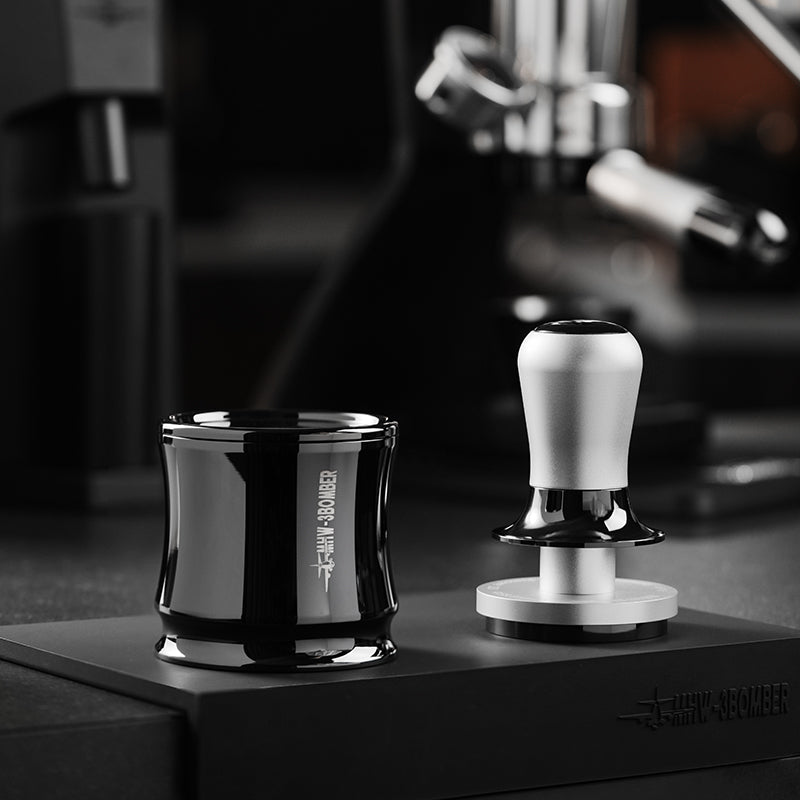 MHW-3BOMBER DR7031B Titanium Black FlowLight dosing chamber with lid on a coffee station; adjacent tamper and machine are not included