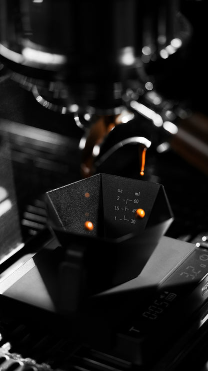 MHW-3BOMBER Black Prism cup under an espresso spout, interior graduation view