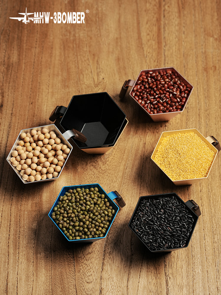 MHW-3BOMBER G5775 black Prism cup at upper left on a wooden surface; other cups and dry ingredients are display props