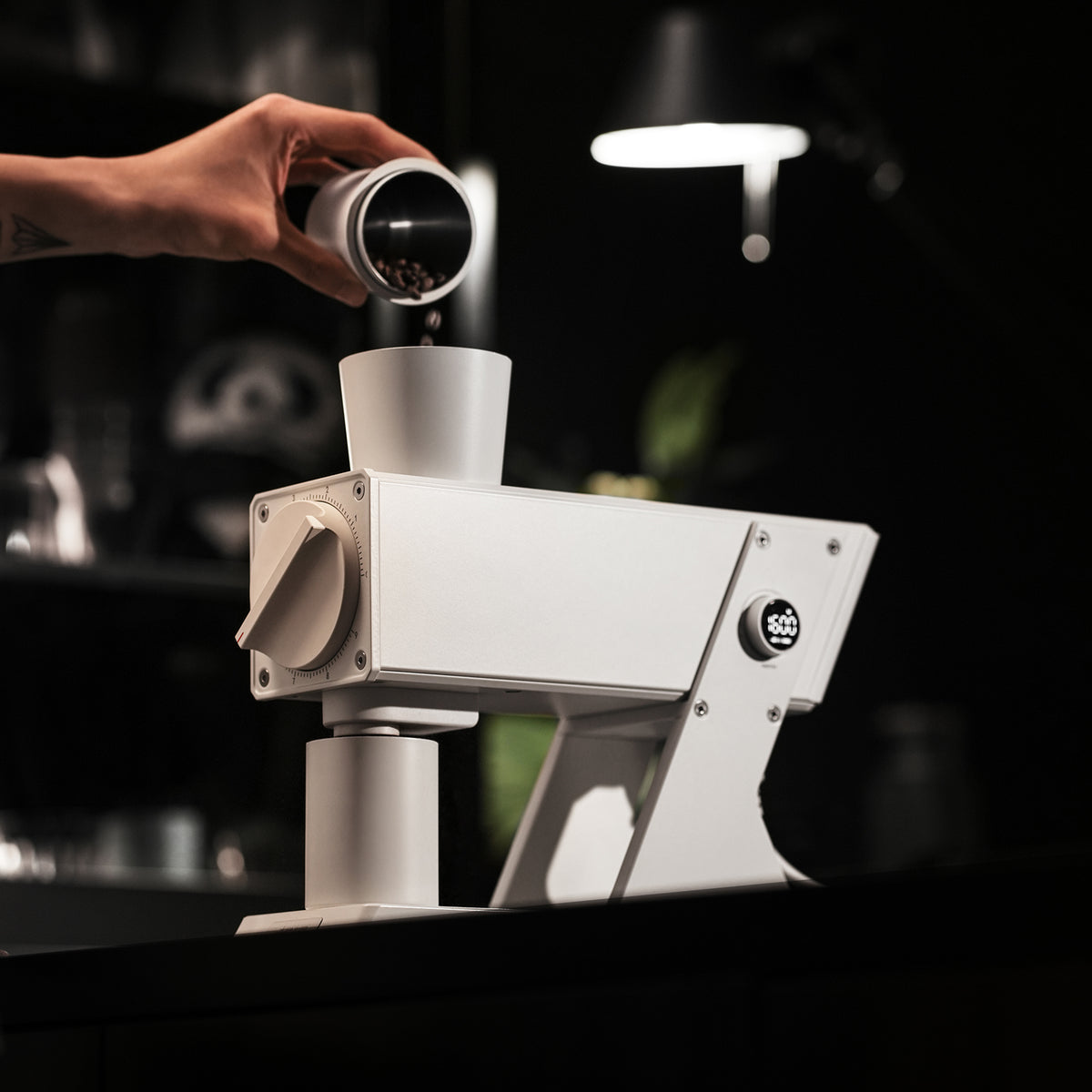 White F74 Navigator grinder in use with a hand holding a dosing cup; scene props not included.