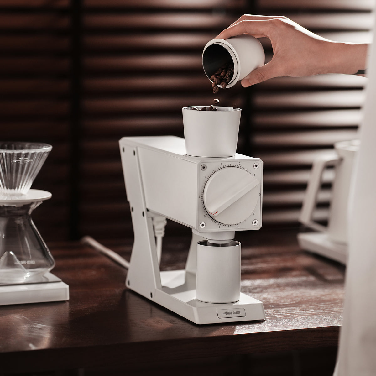 White F74 Navigator grinder while beans are poured into its hopper; brewing props not included.