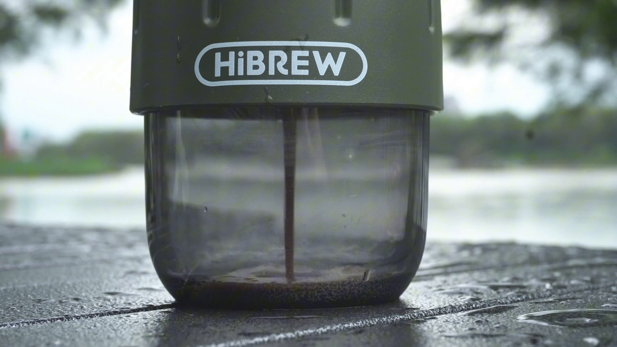 Espresso collecting in the transparent cup of the Green HiBREW H4D manual brewer