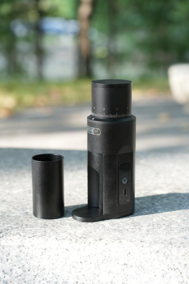 Black HiBREW G5mini grinder on an outdoor table with its grounds cup removed