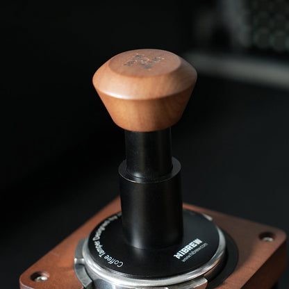 HiBREW Master wood-handled black tamper seated in a portafilter on a tamping station; portafilter and station are demonstration props, not included.