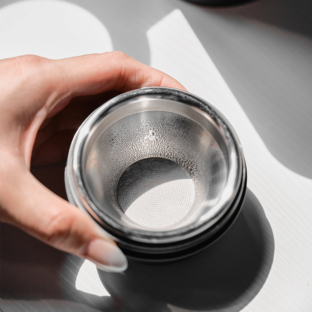 Hand holding a convex espresso basket with a 32 mm paper filter fitted inside