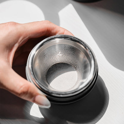 Hand holding a convex espresso basket with a 32 mm paper filter fitted inside