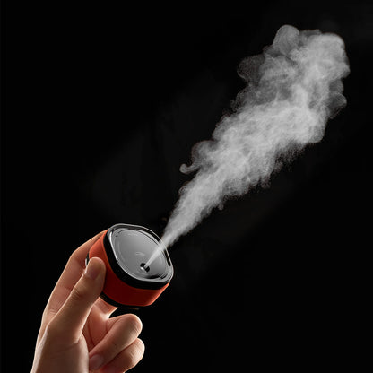 IKAPE electric coffee bean atomizer, black and orange, held upright showing spray direction