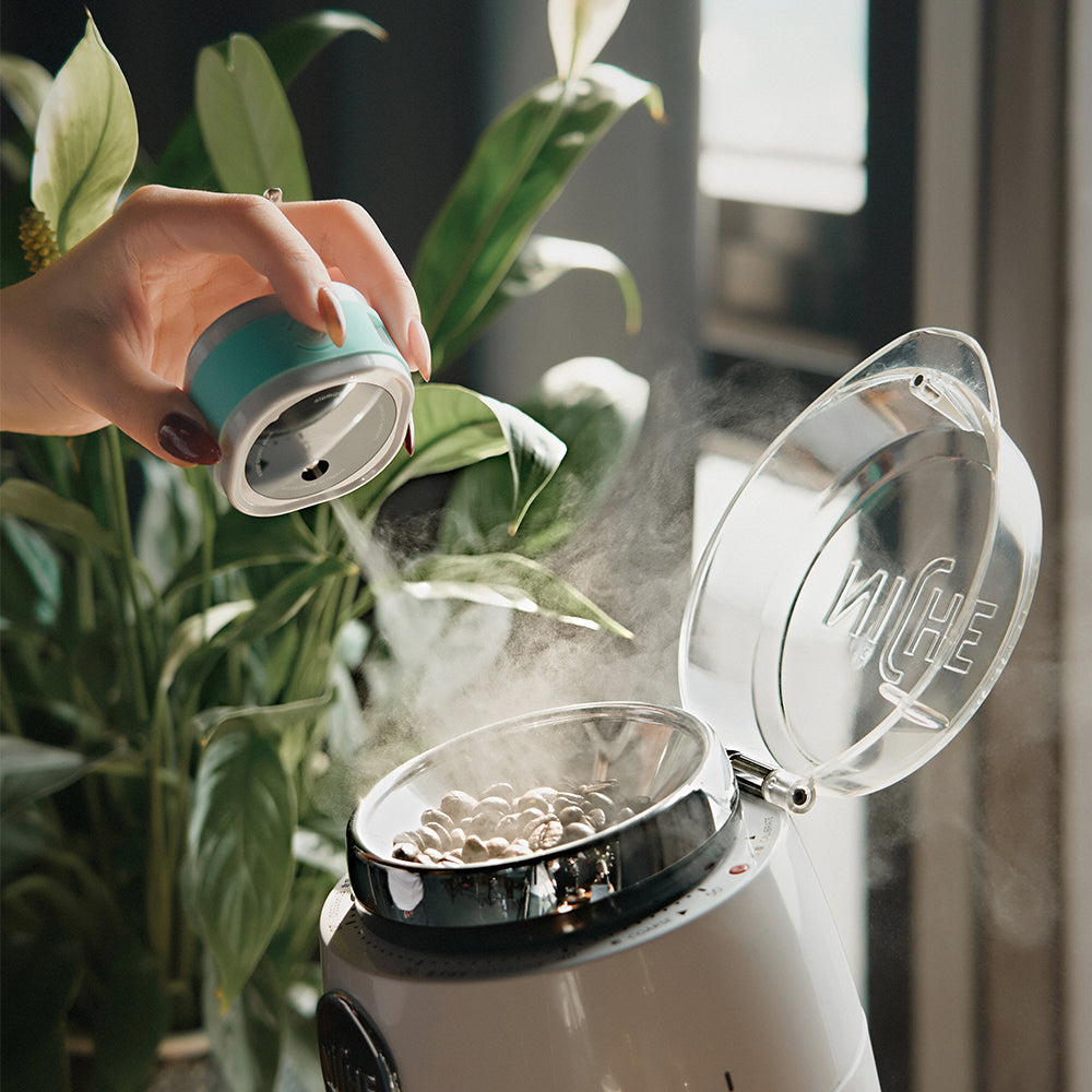IKAPE electric coffee bean atomizer, white and blue, spraying beans into grinder