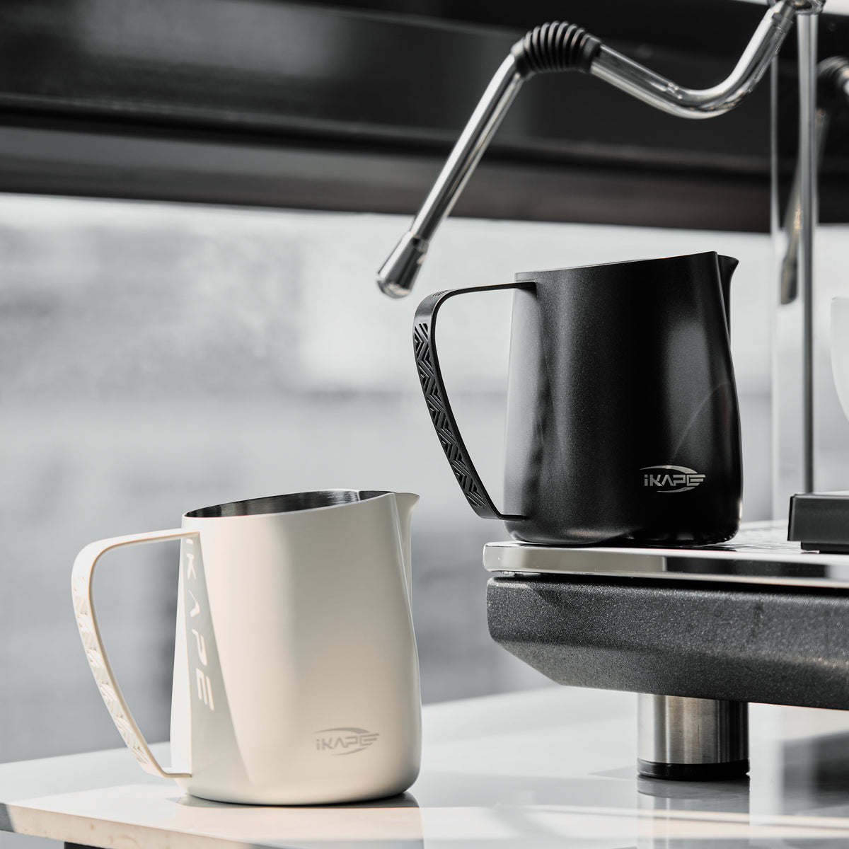 White and Black IKAPE hollow-handle milk pitchers beside an espresso machine; each option includes one pitcher