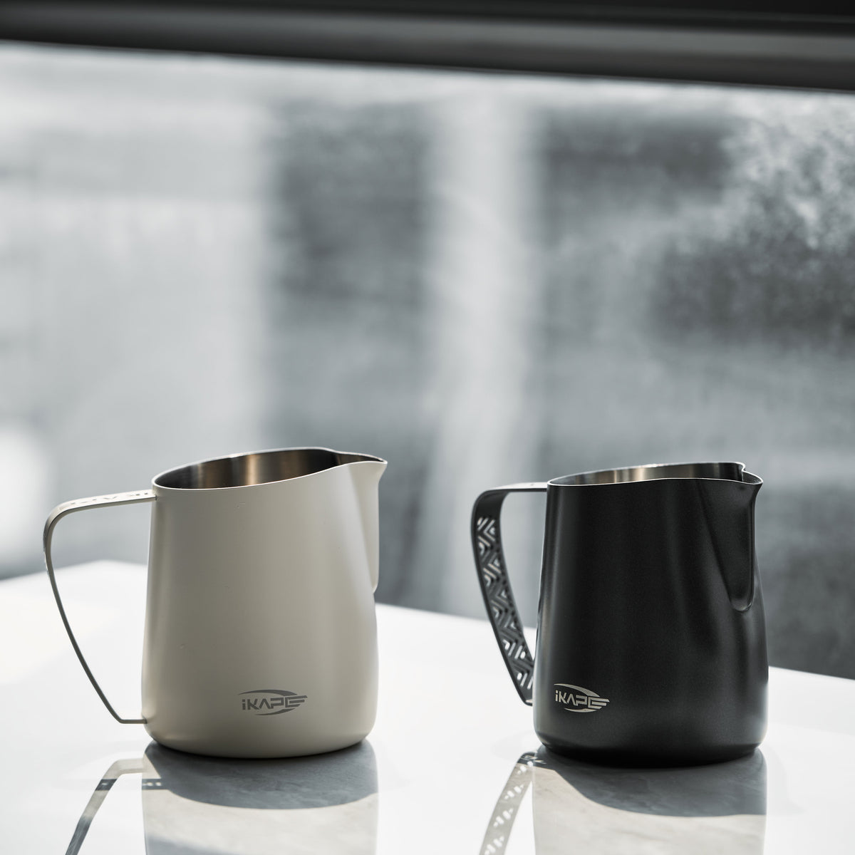 White and Black IKAPE hollow-handle milk pitchers on a countertop; each option includes one pitcher
