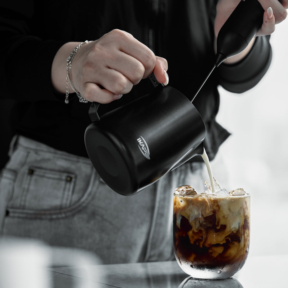Black IKAPE hollow-handle milk pitcher pouring milk into iced coffee