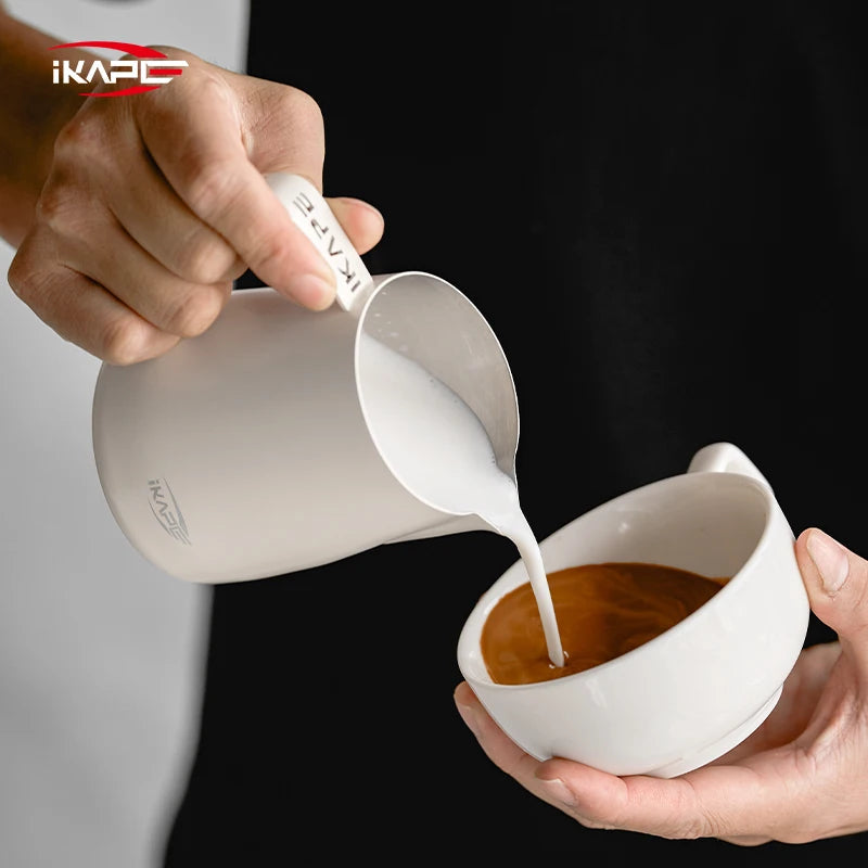 White IKAPE hollow-handle milk pitcher pouring milk into an espresso cup