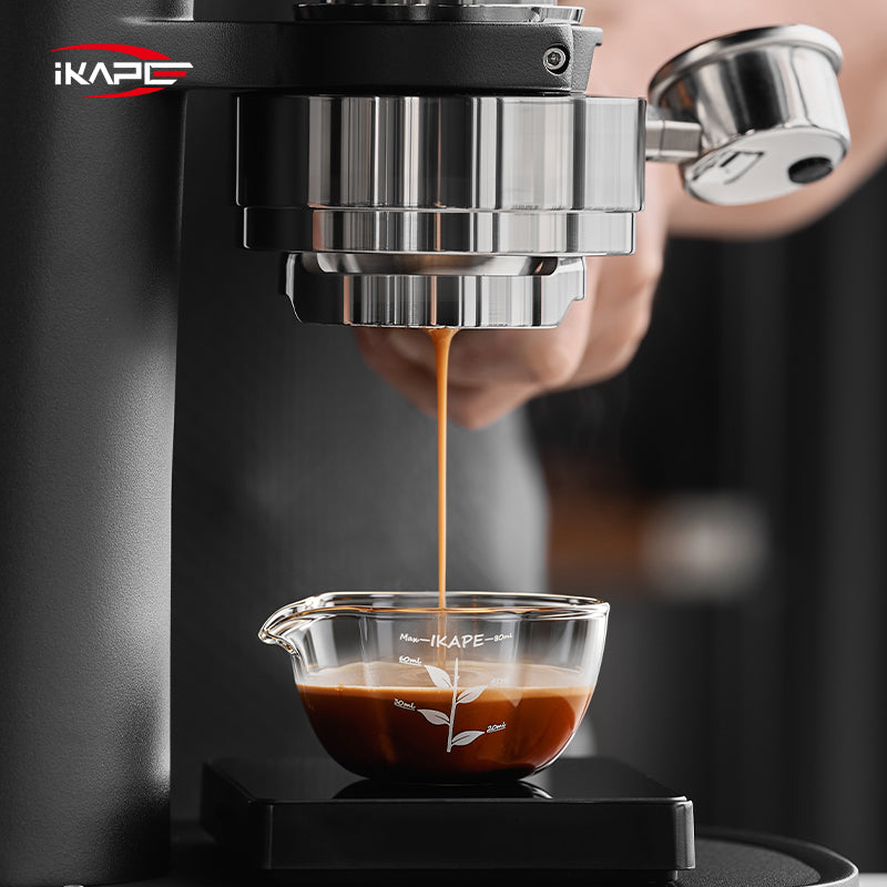 IKAPE Glass Petal measuring cup beneath a bottomless espresso portafilter
