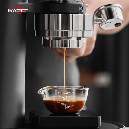 IKAPE Glass Petal measuring cup beneath a bottomless espresso portafilter