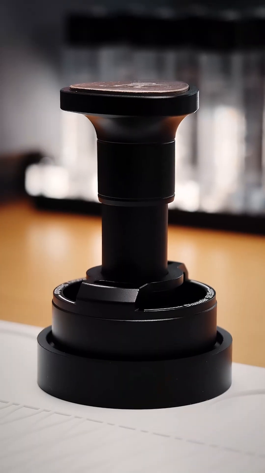 IKAPE UniPress 58.35 mm distributor and tamper, standing view with shaped palm grip.