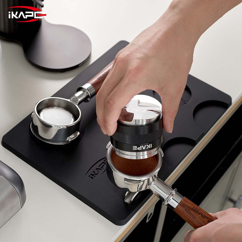 IKAPE V1 black silicone tamping mat during distribution; tools shown are props and not included