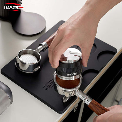 IKAPE V1 black silicone tamping mat during distribution; tools shown are props and not included