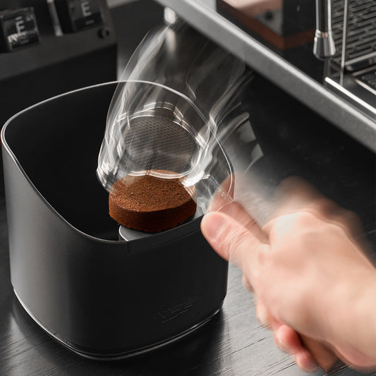 IKAPE V2 black ABS knock box in use with a portafilter; demonstration equipment excluded
