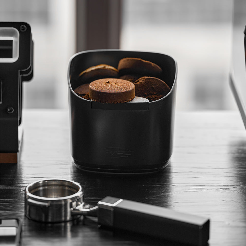 IKAPE V2 black knock box on a coffee counter; separate portafilter excluded