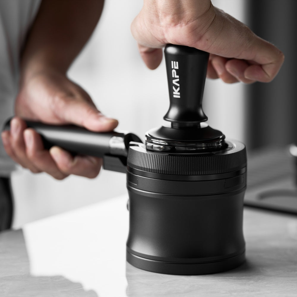 IKAPE V4 black rotary adjustable portafilter stand, manufacturer usage photograph 3; shown portafilter and preparation tools are props