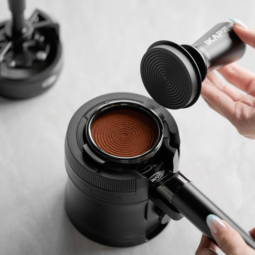 IKAPE V4 black rotary adjustable portafilter stand, manufacturer usage photograph 4; shown portafilter and preparation tools are props