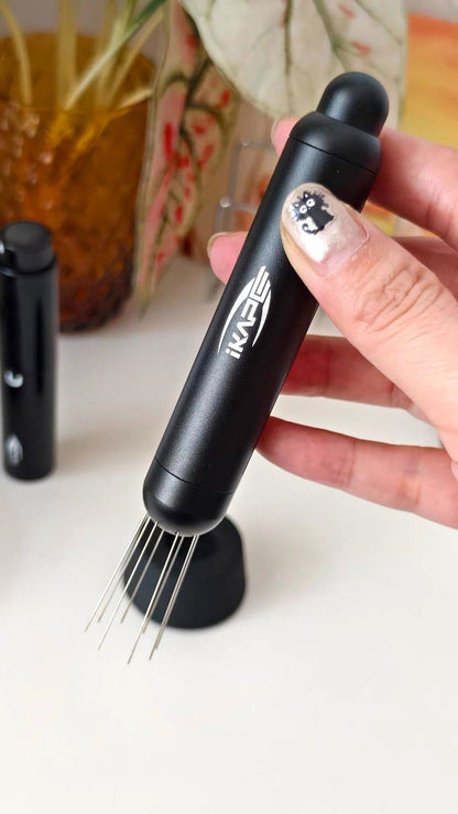 IKAPE black retractable WDT tool with the needles extended, held in hand