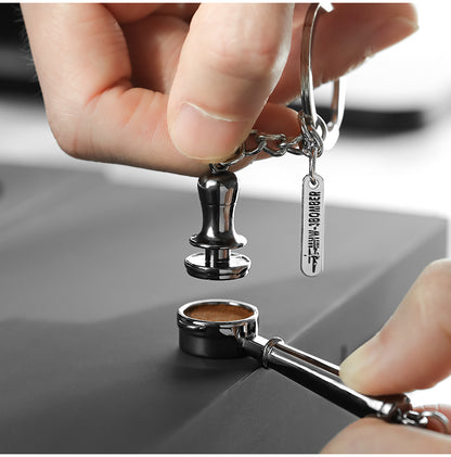KC5701 miniature tamper keychain held above a full-size portafilter; portafilter is a photography prop