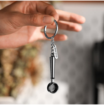 KC5702 miniature bottomless-portafilter keychain suspended from its keyring in a hand