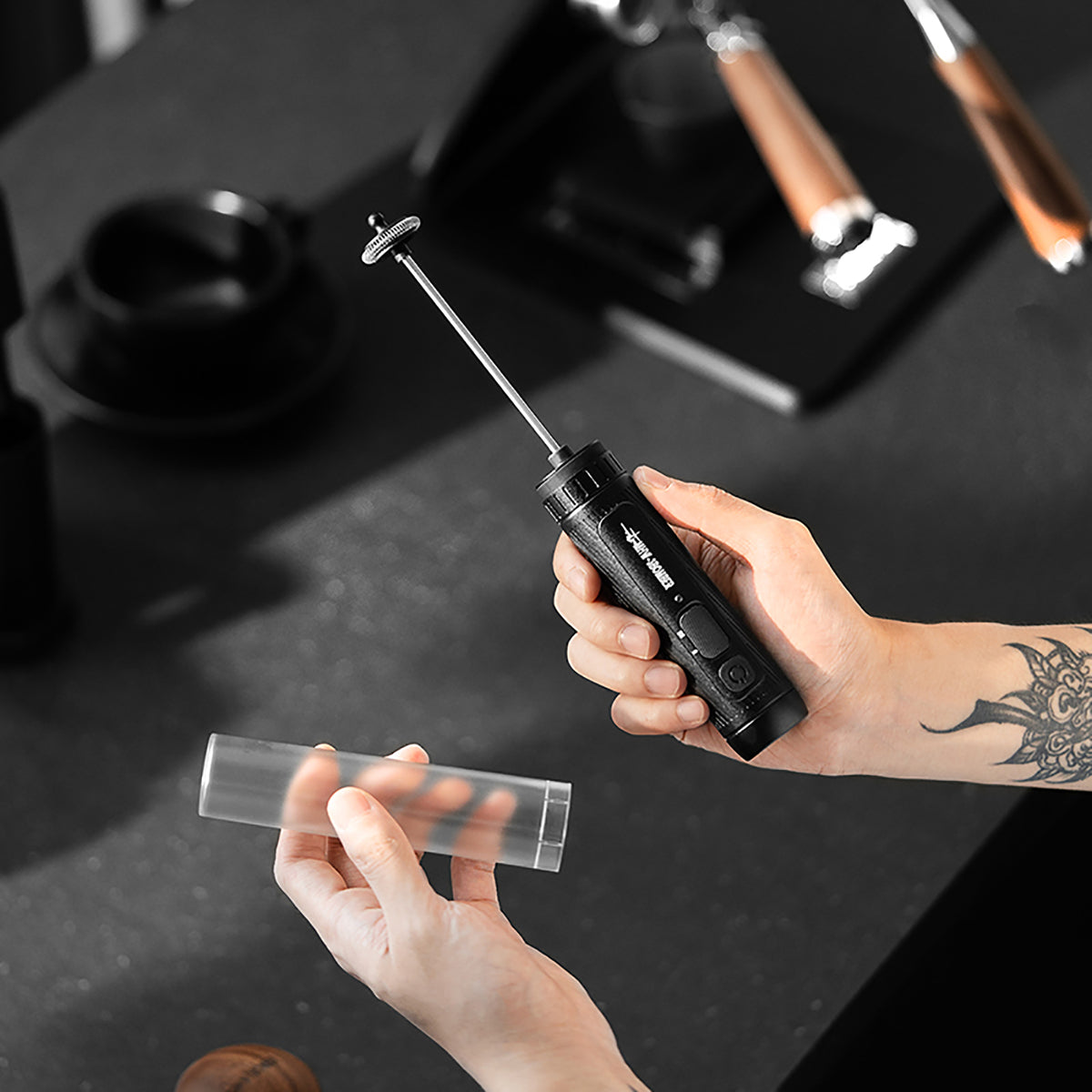 MHW-3BOMBER MF5893 black Magician frother held with its protective sleeve removed; café equipment not included