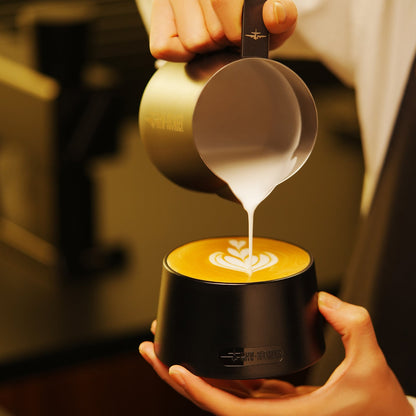 MHW-3BOMBER black cupping bowl held during latte pouring; milk pitcher and drinks are scene props, not included
