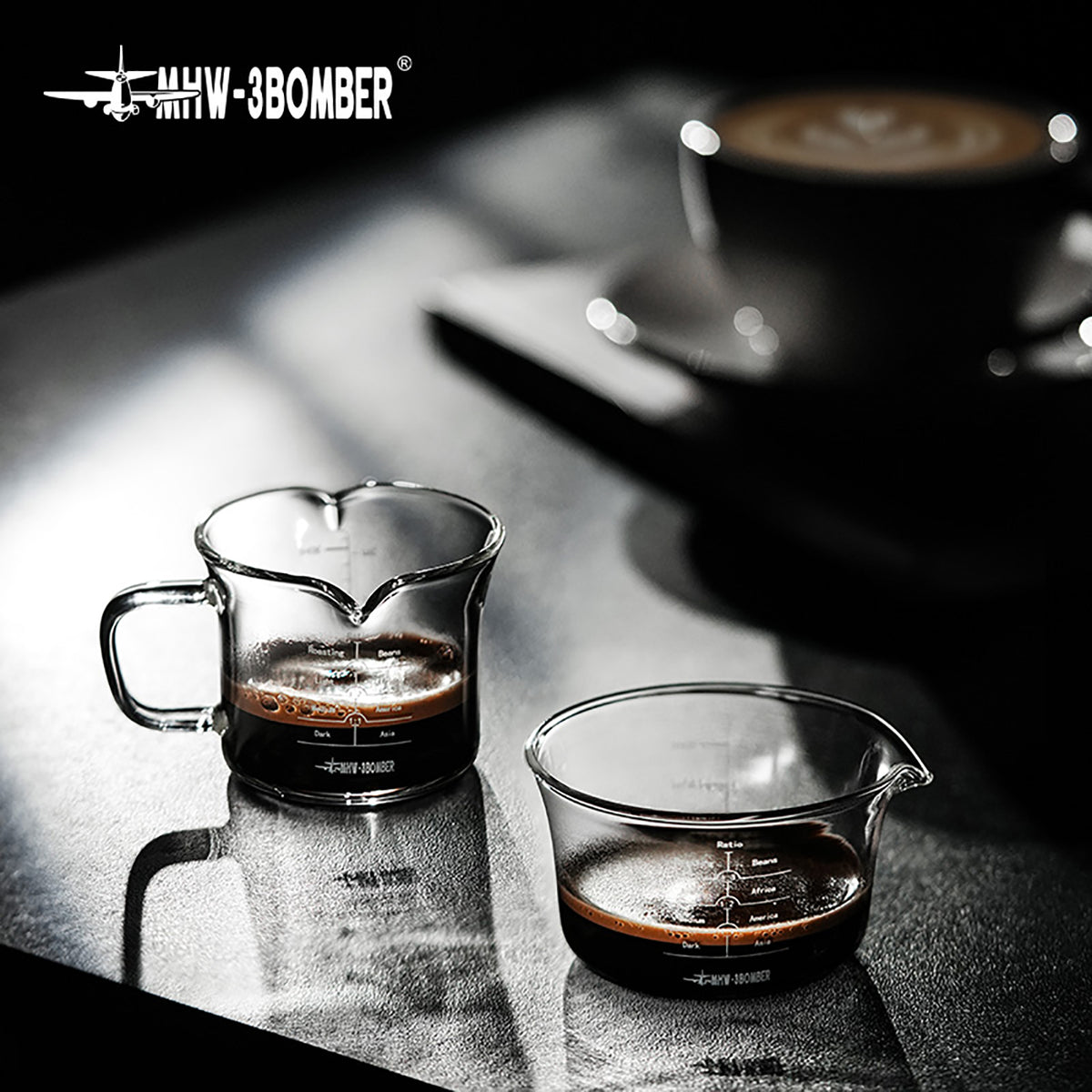 Clear G5059 handled double-spout cup at the back left and G5052 single-spout cup at the front right on a coffee counter; one selected configuration is supplied, other cups and coffee are props