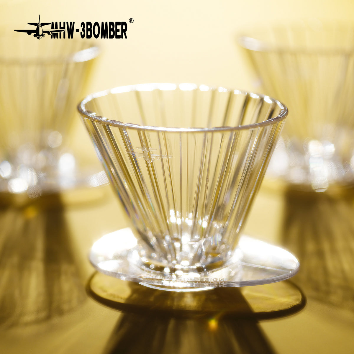 MHW-3BOMBER FC6605 — clear Oval dripper side profile and support base in warm light; other tools are scene props