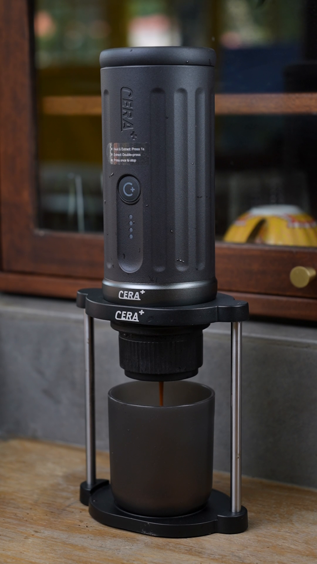 CERA+ PCM03S Space Grey extracting espresso into its cup on a wooden table; stand sold separately