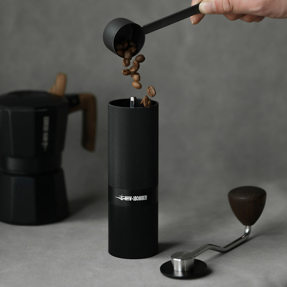 Adding coffee beans to the MHW-3BOMBER Racing M1 black manual grinder with the crank removed