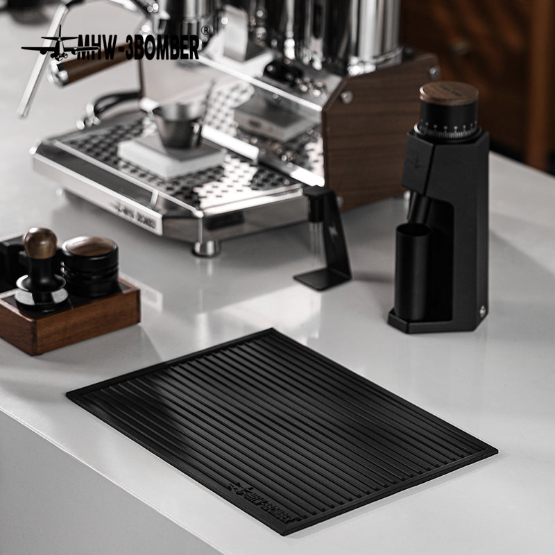 MHW-3BOMBER SP5326B Black dish drying pad lying flat on a coffee counter; pictured tools and equipment not included.