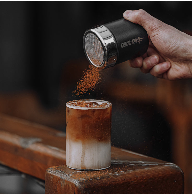 MHW-3BOMBER SP5366B matte black shaker above coffee against a blue background