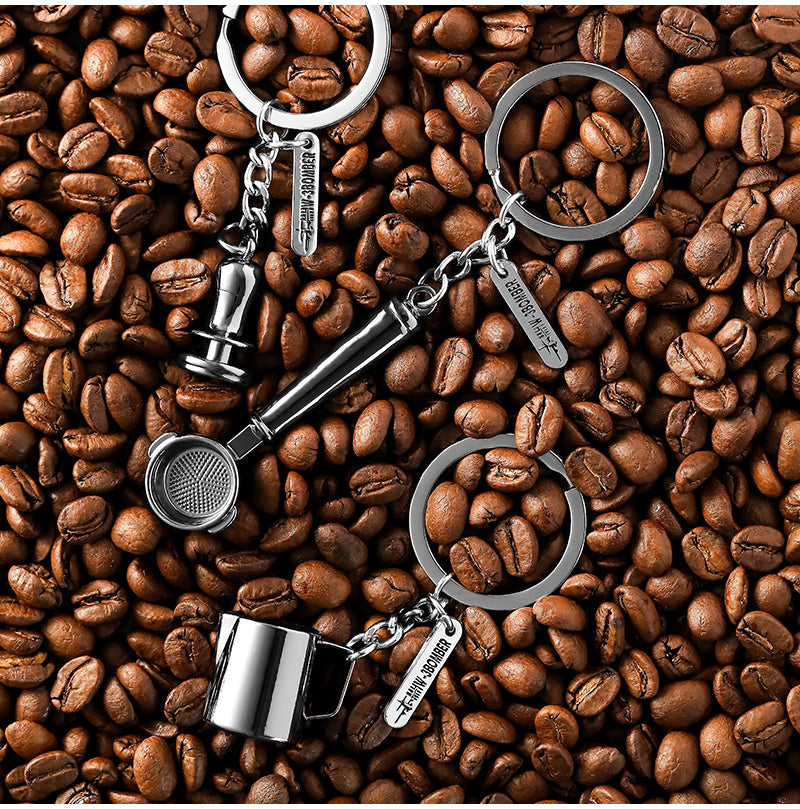 KC5700 pitcher, KC5701 tamper and KC5702 portafilter keychains arranged on coffee beans; comparison photo, select one individual SKU